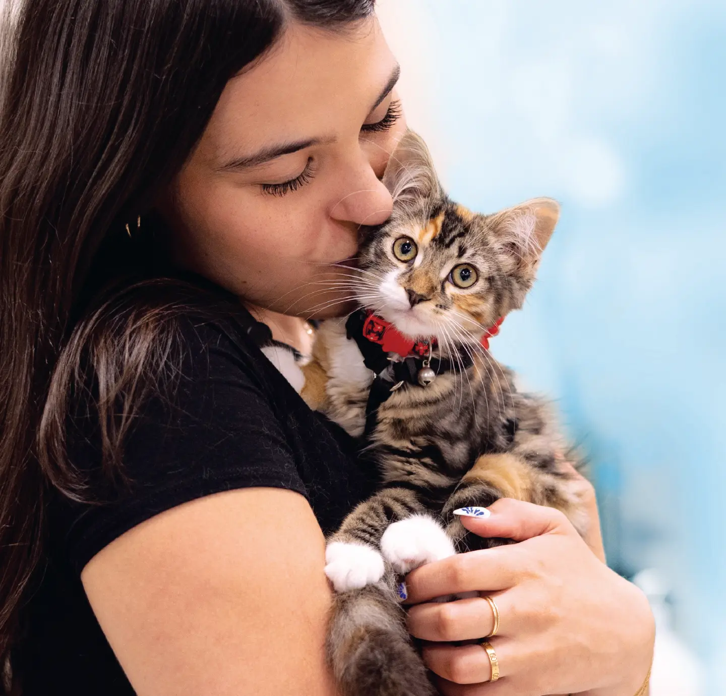 Woman kisses a cat she's holding in her arms